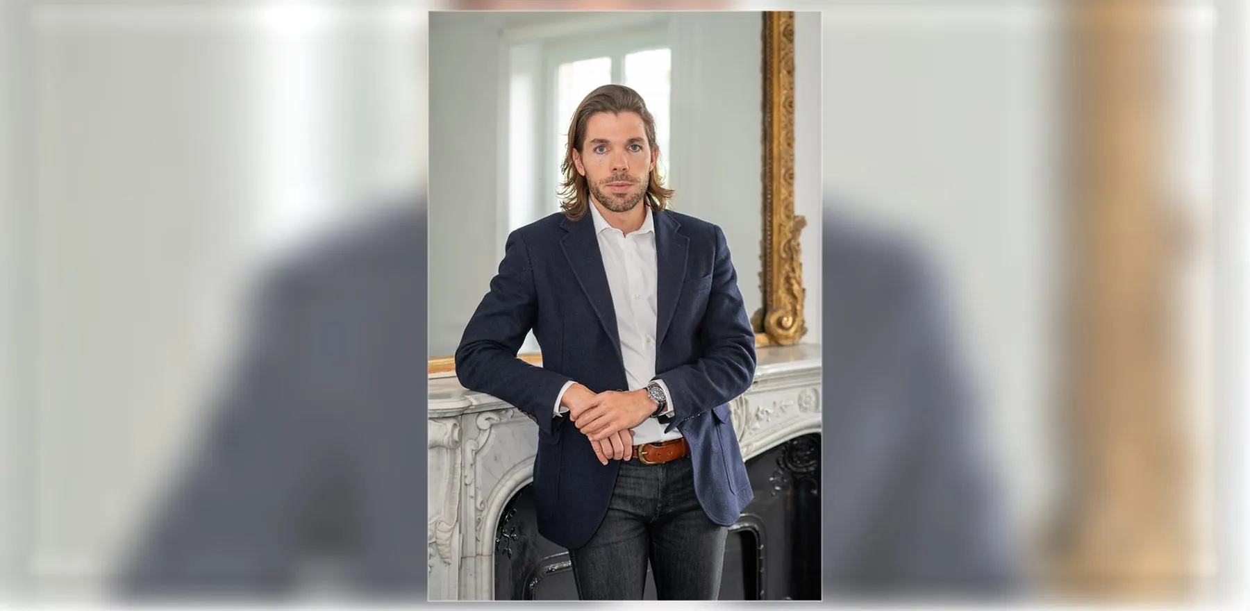 Portrait d'un homme en blazer, accoudé à une cheminée ancienne